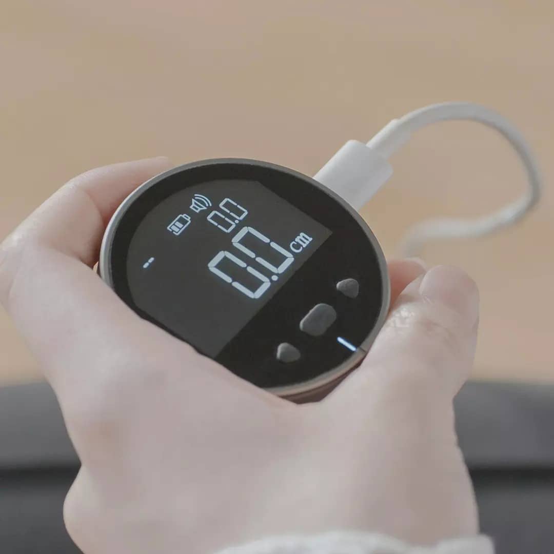 Black Mesauer Digital Electronic Measuring Ruler with digital display held in hand connected by white cable